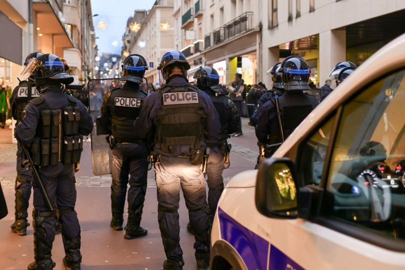 Police officers in riot gear on a city street — the tension between public safety and civil liberties